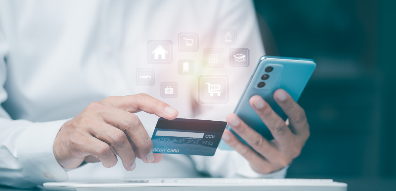 Hands holding a credit card in one hand and a phone in the other hand.