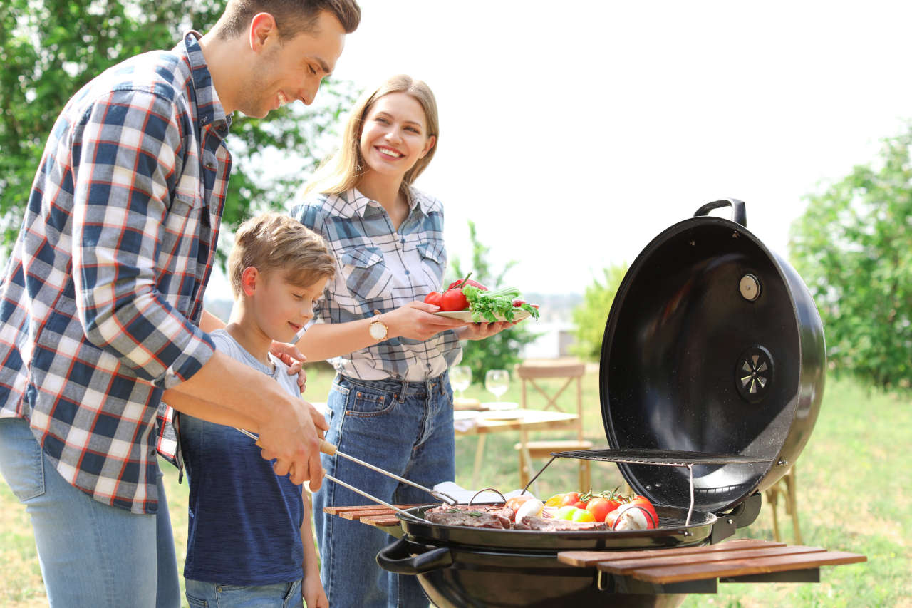a man, woman and a kid standing infront of a grill